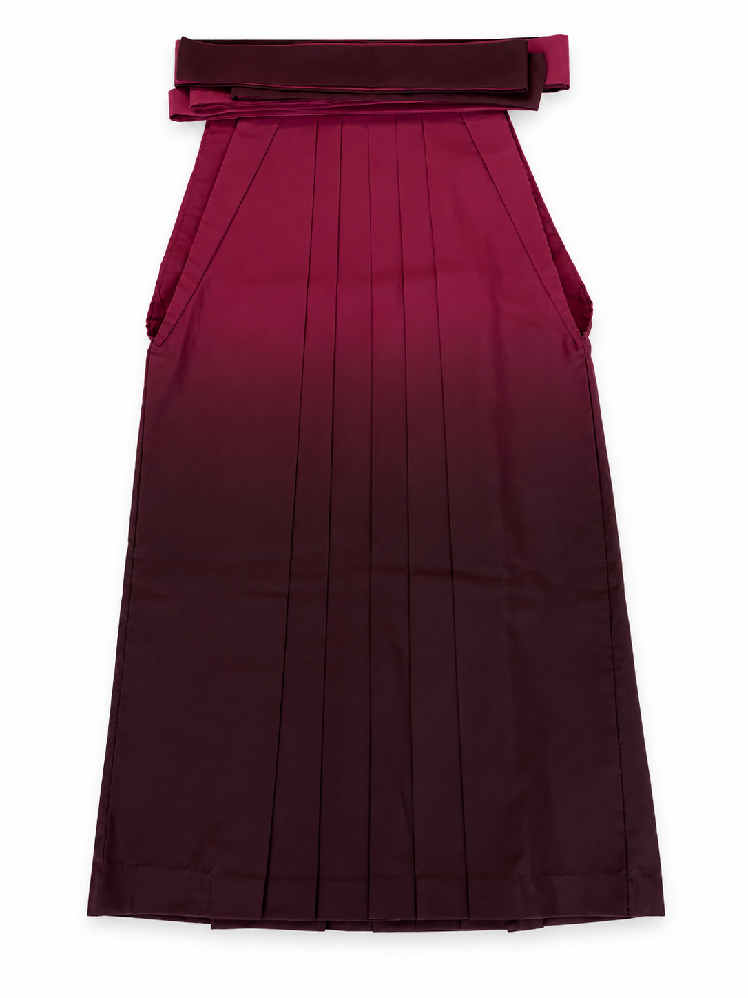 A pleated traditional Japanese hakama skirt with a wide waistband and bow detail, shown flat against a plain white background. The hakama features a deep wine red to dark burgundy ombré color gradient.