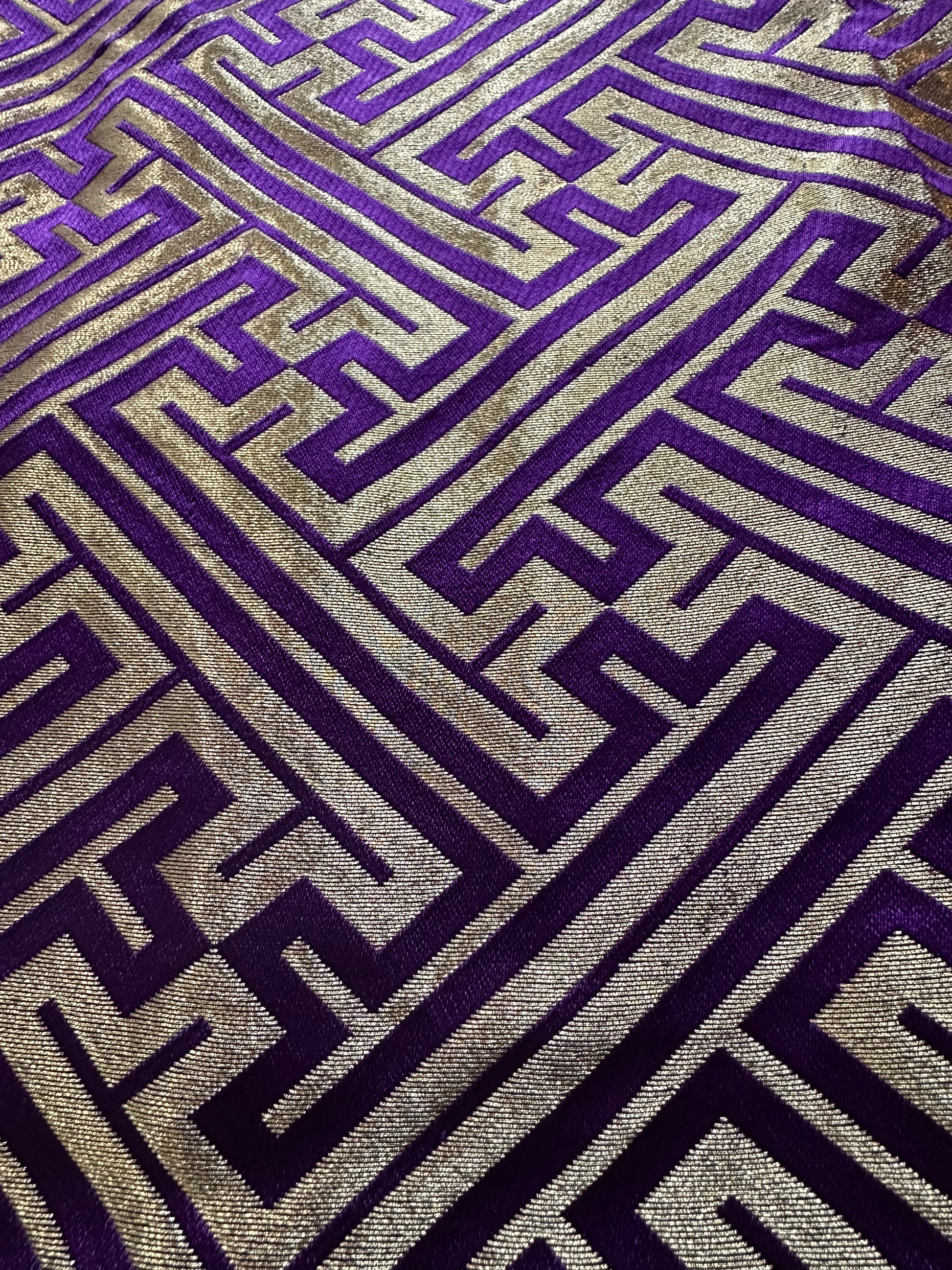 A close-up of a hakama fabric with a geometric Greek key pattern in deep purple and metallic gold.