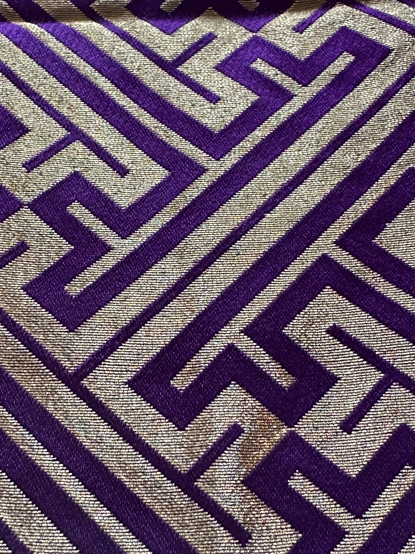 A close-up of a hakama fabric with a geometric maze-like pattern in deep purple and metallic gold.