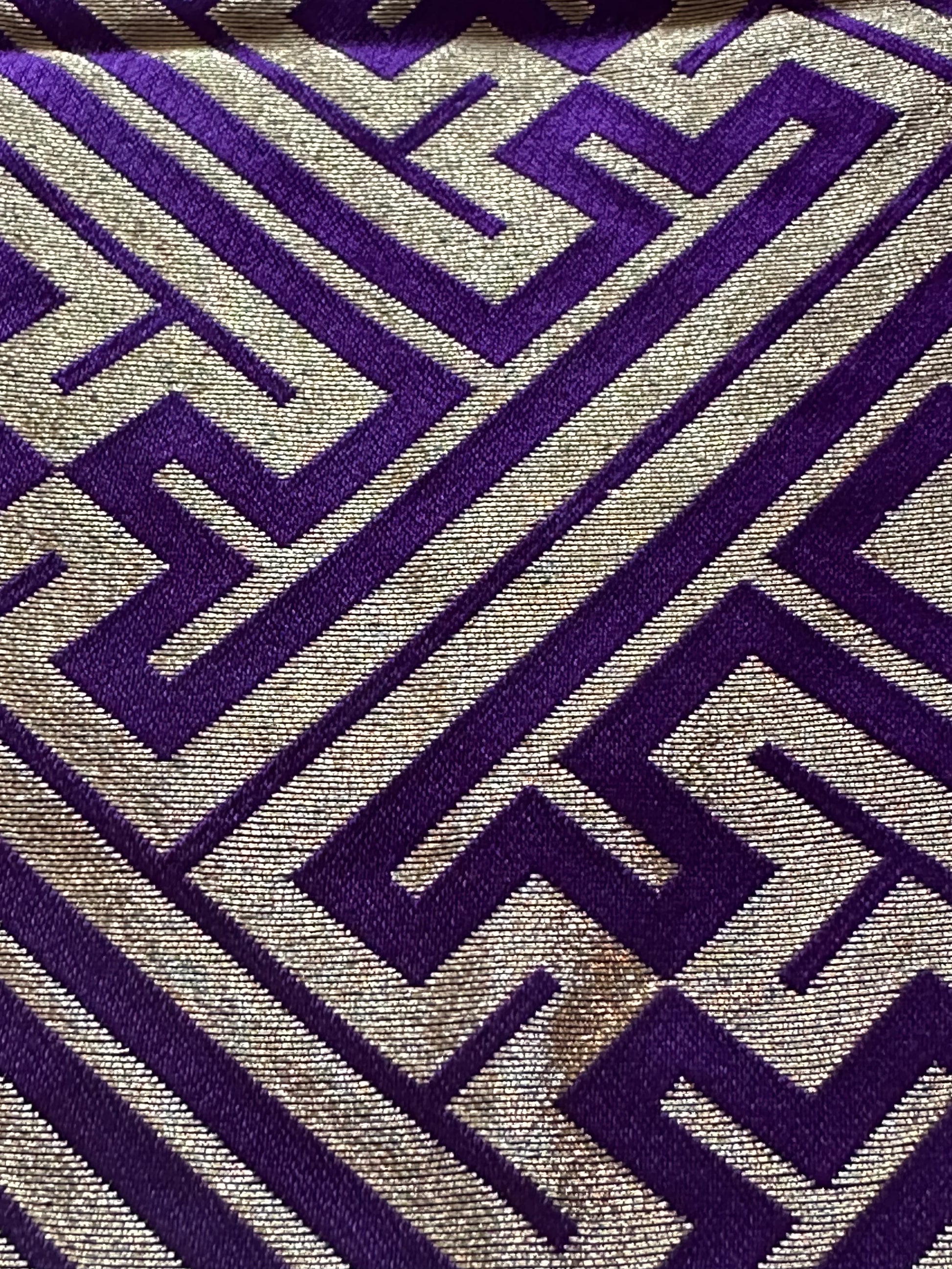 A close-up of a hakama fabric with a geometric maze-like pattern in deep purple and metallic gold.