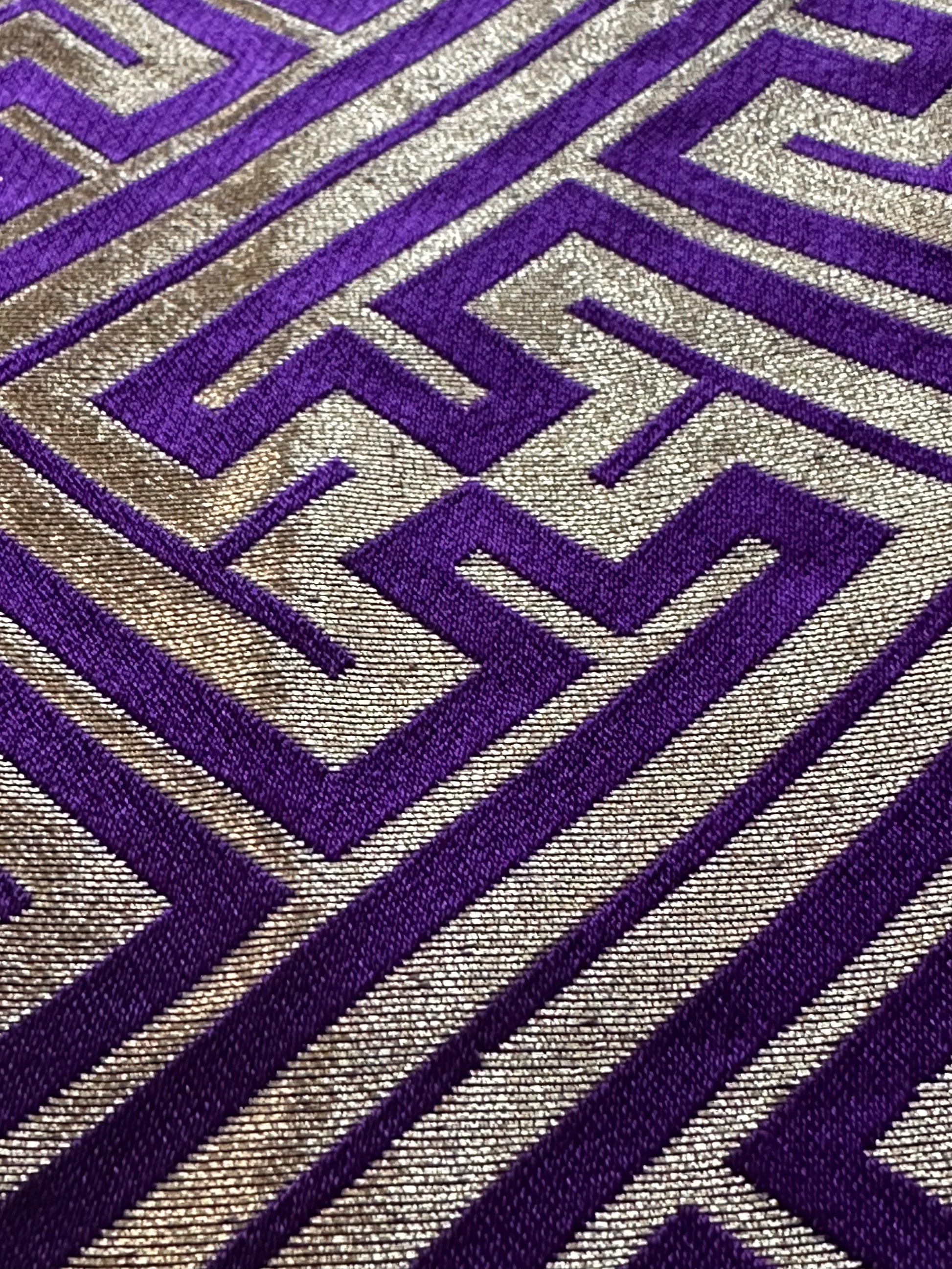 A close-up of a hakama fabric with a geometric maze-like pattern in deep purple and metallic gold.