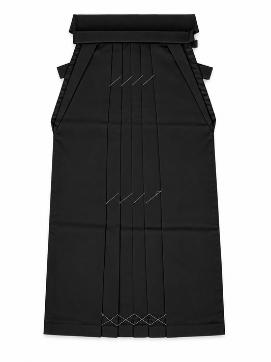 A black traditional Japanese hakama skirt with  vertical front pleats accented with geometric white stitched details, shown against a plain white background.