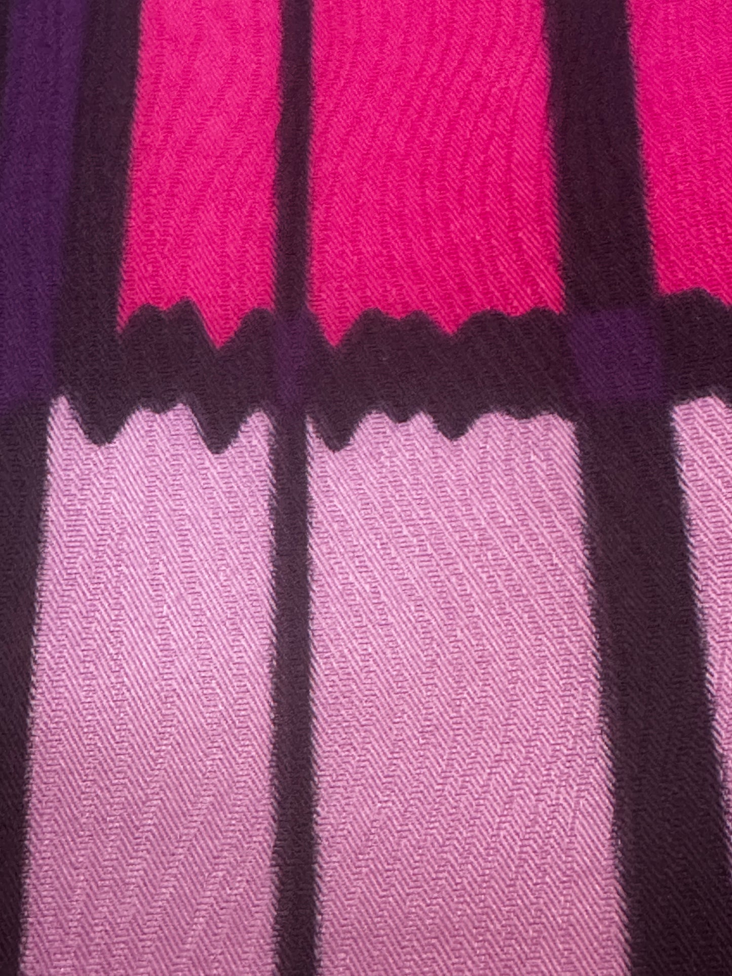 A close-up of a woven textile pattern featuring alternating vertical panels in bright pink, light lavender, and deep purple, separated by thick dark purple vertical stripes and a scalloped wavy border.