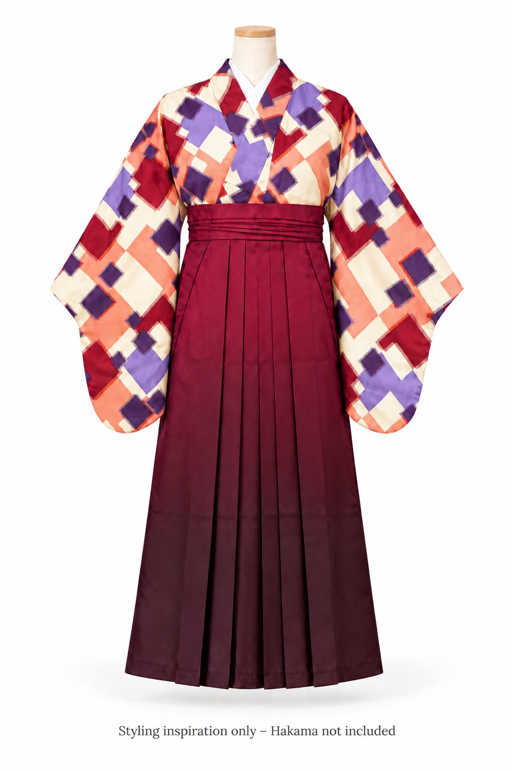 A traditional Japanese furisode kimono and hakama set displayed on a mannequin against a white background. The kimono features a geometric patterned pattern in red, purple, orange, and cream, paired with a solid deep burgundy pleated hakama skirt. With a message at the botton "Styling inspiration only - hakama not included"